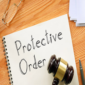Handwritten Protective Order in a notebook with a gavel; legal steps for safety and relief.